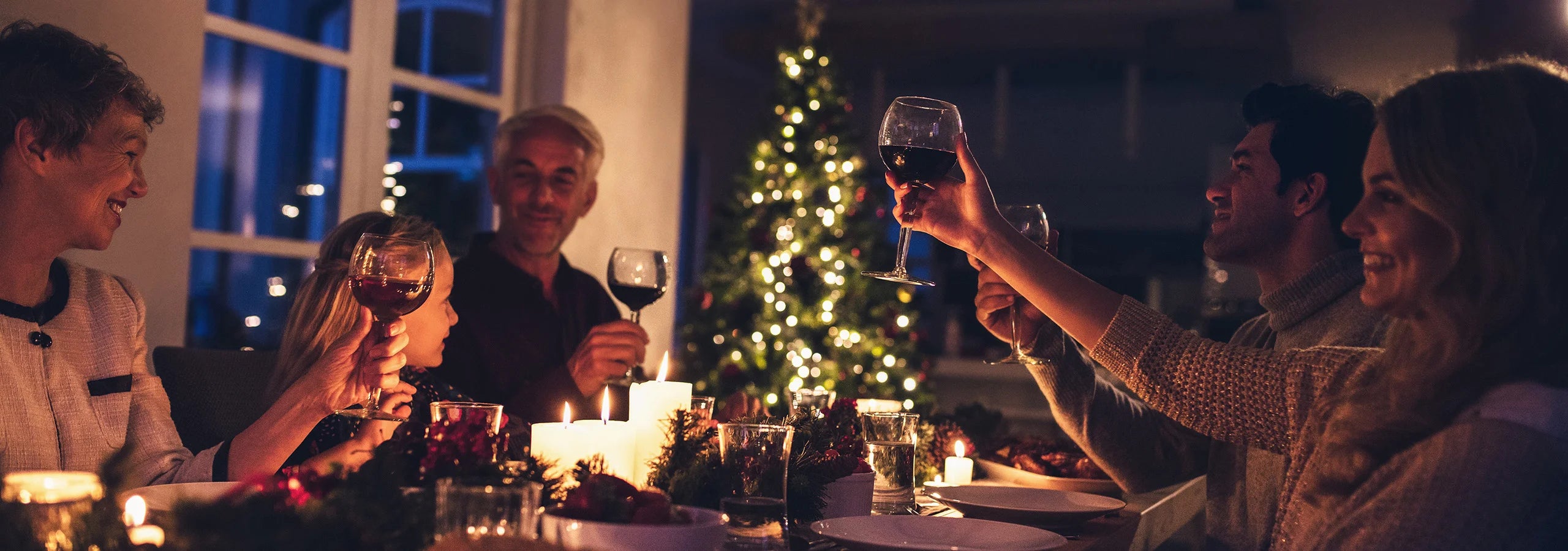 Familie beim Anstoßen an einem weihnachtlich gedeckten Tisch